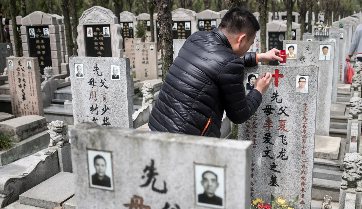 Seorang pria mengecat ulang batu nisan makam keluarga mereka saat festival Qingming di Shanghai (6/6). Festival tradisional Tiongkok ini dilaksanakan pada hari ke-104 setelah titik balik Matahari di musim dingin. (AFP/Johannes Eisele)