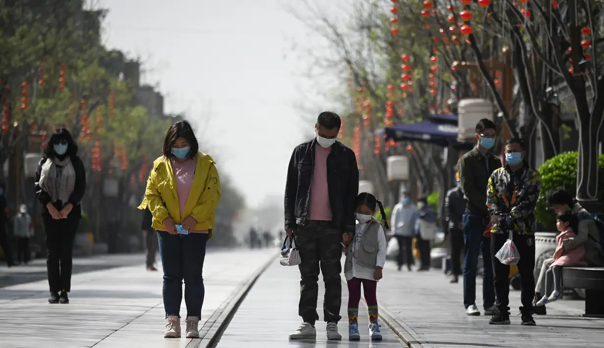 Orang-orang mengenakan masker membungkuk tiga menit selama peringatan nasional untuk memperingati korban meninggal dalam wabah virus coronavirus COVID-19 di sepanjang jalan bisnis di Beijing  (4/4/2020). (AFP/Wang Zhao)
