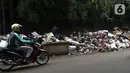 Pengendara melintas disamping tumpukan sampah di sepanjang jalan pascabanjir  di Kembangan, Jakarta Barat, Minggu (5/1/2020). Nantinya sampah-sampah ini akan diangkut oleh petugas kebersihan menggunakan truk pengangkut sampah yang akan dibawa ke TPA Bantar Gebang.  (Liputan6.com/Johan Tallo)