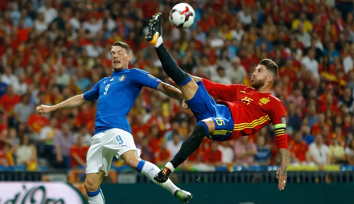 Bek Spanyol, Sergio Ramos berusaha menghalau bola dari kejaran penyerang Italia, Andrea Belotti saat bertanding di kualifikasi Piala Dunia 2018 di Stadion Santiago Bernabeu di Madrid, (2/9). Spanyol menang atas Italia 3-0. (AP Photo / Francisco Seco)