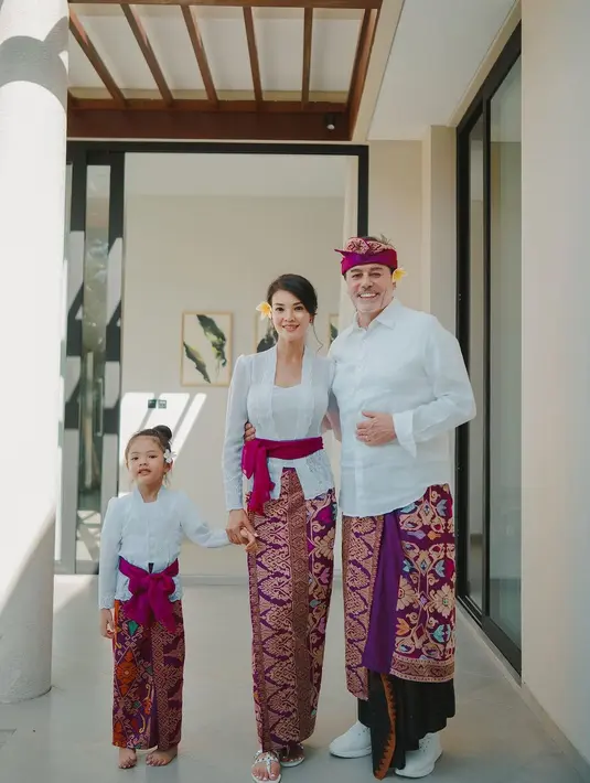 Pembawa acara yang juga chef itu mengenakan busana adat Bali bersama suami dan putrinya. Mereka kompak mengenakan putih dan bawakan kain batik. Penampilannya makin lengkap dengan selendang yang melingkar di perutnya. [Instagram/farahquinnofficial