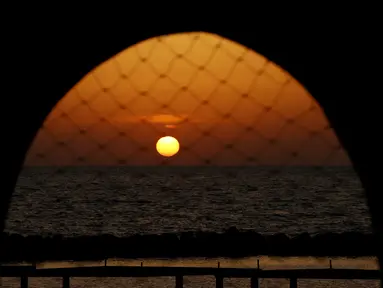 Matahari terbenam di pantai di kota pesisir Mediterania Israel Netanya, utara Tel Aviv (8/6/2021). Netanya adalah sebuah kota yang terletak di Israel. Kota ini terletak di antara sungai kecil Poleg dan insitut Wingate di selatan dan di sebelah utara terdapat sungai kecil "Avichail". (AFP/ Jack Guez)