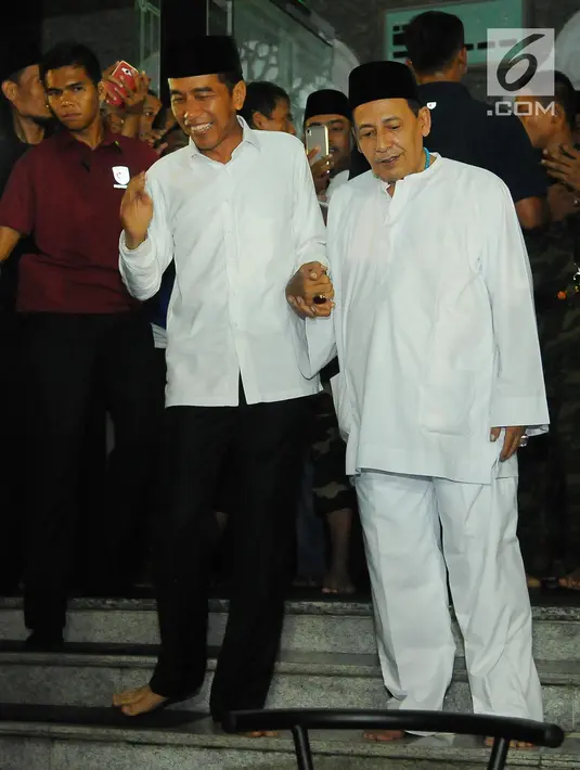Capres nomor urut 01 Joko Widodo atau Jokowi (kiri) menggandeng Habib Luthfi bin Yahya usai menjalankan ibadah dalam kampanye terbuka di Alun-Alun Brebes, Jawa Tengah, Kamis (4/4). Jokowi menargetkan kemenangan lebih dari 80 persen di Brebes. (Liputan6.com/Angga Yuniar)