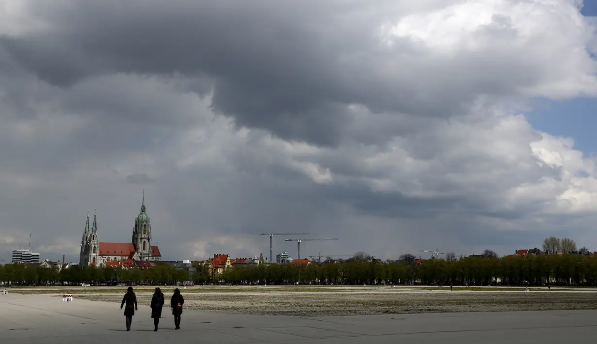 Orang-orang berjalan di area Theresienwiese, tempat festival bir 'Oktoberfest' diadakan, di depan gereja St. Pauls, di Munich, Jerman pada Senin (3/5/2021). Jerman kembali membatalkan festival bir Oktoberfest untuk tahun kedua karena pandemi covid-19. (AP Photo/Matthias Schrader)