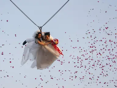 Jintara Promchat dan Kittinant Suwansiri bergelantungan pada tali saat upacara pernikahan di Ratchaburi, Thailand, Sabtu (13/2). Upacara pernikahan tersebut diikuti oleh empat pasang pengantin untuk menyambut Hari Valentine. (REUTERS/ Athit Perawongmetha)