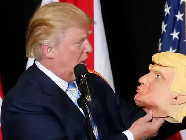 Capres dari Partai Republik Donald Trump melihat topeng wajah dirinya saat berkampanye di Sarasota, Florida, AS (7/11). Pilpres AS 2016 akan diadakan pada 8 November 2016 dan menjadi pilpres empat tahunan ke-58.  (REUTERS/Carlo Allegri) 