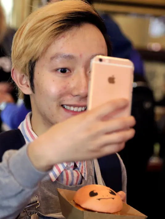 Pengunjung berselfie dengan burger 'Pokeburg' karakter dari game fenomena Pokemon Go di restoran Down N 'Out Burger, Sydney, Australia, (26/8). (REUTERS/Jason Reed)