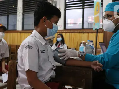 Petugas menyuntikan vaksin COVID-19 Pfizer kepada seorang siswa di SDN Panunggangan 5, Pinang, Kota Tangerang, Selasa (19/10/2021).  Pelaksanaan vaksinasi untuk pelajar usia 12 tahun ini dilakukan dalam rangka persiapan pelaksanaan pembelajaran tatap muka (PTM). (Liputan6.com/Angga Yuniar)