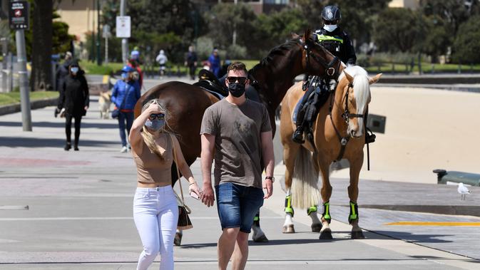 Polisi berpatroli dengan menunggang kuda di sepanjang St Kilda Esplanade di Melbourne (26/10/2020). Australia telah menghabiskan berbulan-bulan di bawah pembatasan yang berat setelah menjadi episentrum gelombang kedua negara itu. (AFP Photo/William West)