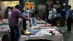 Sebagian siswi mendapat perawatan di lorong rumah sakit menyusul kebocoran gas dari sebuah depot kontainer di New Delhi, India, Sabtu (6/5). Lebih dari 100 murid dievakuasi dari sekolah Rani Jhansi di New Delhi dalam insiden tersebut. (Chandan KHANNA/AFP)