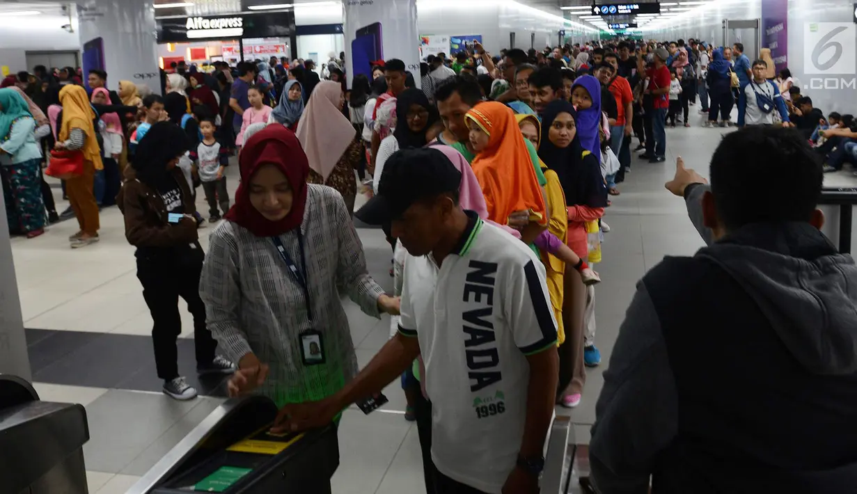 Petugas membantu calon penumpang melakukan tap kartu saat akan menggunakan layanan transportasi Moda Raya Terpadu (MRT) di Stasiun Bundaran HI, Jakarta, Rabu (3/4). Meski sudah tidak digratiskan, warga tetap antusias menjajal MRT. (merdeka.com/Imam Buhori)