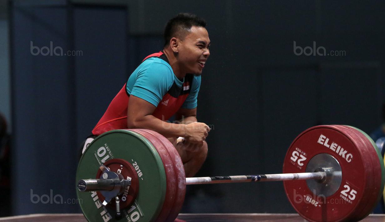 Senyum Lifter Indonesia, Eko Yuli Irawan usai mengangkat beban 135 kg snacth saat turun pada kelas 62 kg di Hall A Arena PRJ, Jakarta, Rabu (11/2/2018). Eko berhasil menyabet medali emas. (Bola.com/Nicklas Hanoatubun)