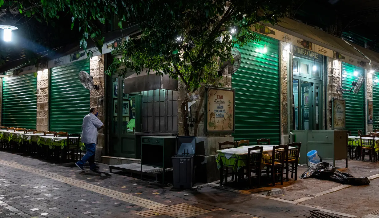 Seorang pria memasuki restoran yang tutup di Athena, Yunani, Minggu (25/10/2020). Pemerintah Yunani telah memberlakukan jam malam di Athena, Thessaloniki, dan daerah lain dengan tingkat infeksi COVID-19 yang tinggi serta kewajiban penggunaan masker. (AP Photo/Yorgos Karahalis)
