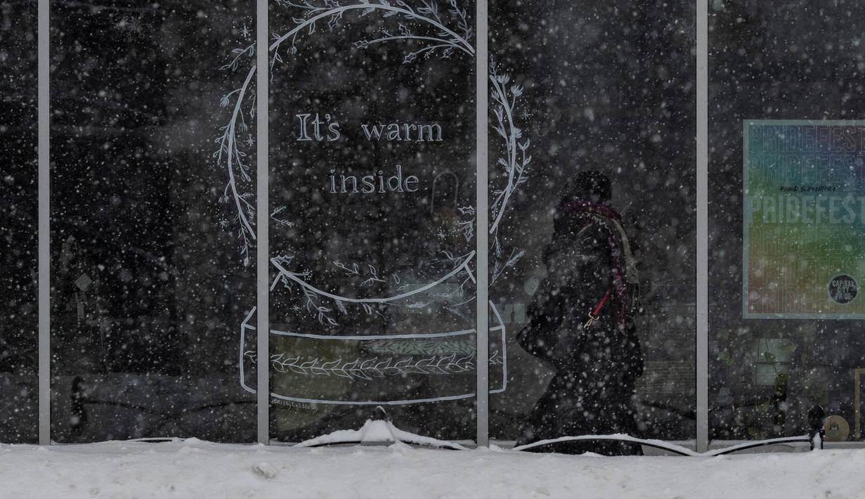 Seseorang berjalan di trotoar yang tertutup salju di lingkungan East Village, Des Moines, Iowa, pada tanggal 12 Januari 2024. (Christian MONTERROSA/AFP)