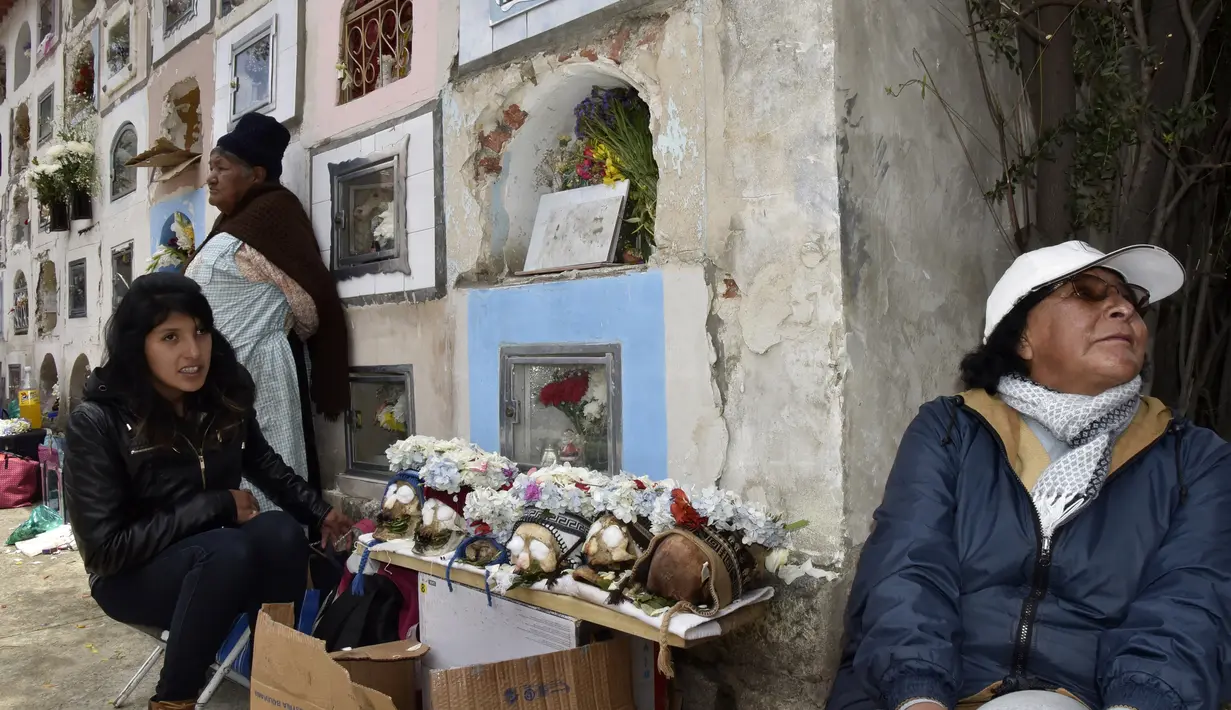 Wanita pribumi Aymara menyembah tengkorak manusia selama Festival Natitas di pemakaman La Paz, Bolivia pada 8 November 2018.  Menurut tradisi Andean, orang-orang percaya menjaga "natitas" di rumah dapat melindungi keluarga mereka. (AIZAR RALDES/AFP)