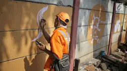 Petugas PPSU membuat mural bertema Asian Games di kawasan Cawang, Jakarta, Selasa (17/7). Mural tersebut dibuat untuk sosialisasi sekaligus bentuk dukungan terhadap perhelatan Asian Games pada Agustus 2018 mendatang. (Liputan6.com/Faizal Fanani)