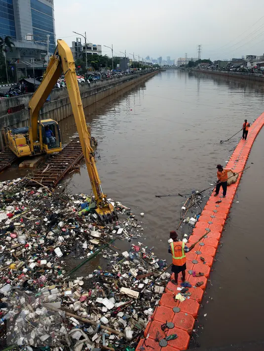 Petugas kebersihkan dibantu alat berat membersihkan sampah di Sungai Kanal Banjir Barat, Jakarta, Senin (14/11). Hujan yang terjadi di hulu Banjir Kanal Barat mengakibatkan meningkatnya debit air yang disertai sampah. (Liputan6.com/Johan Tallo)
