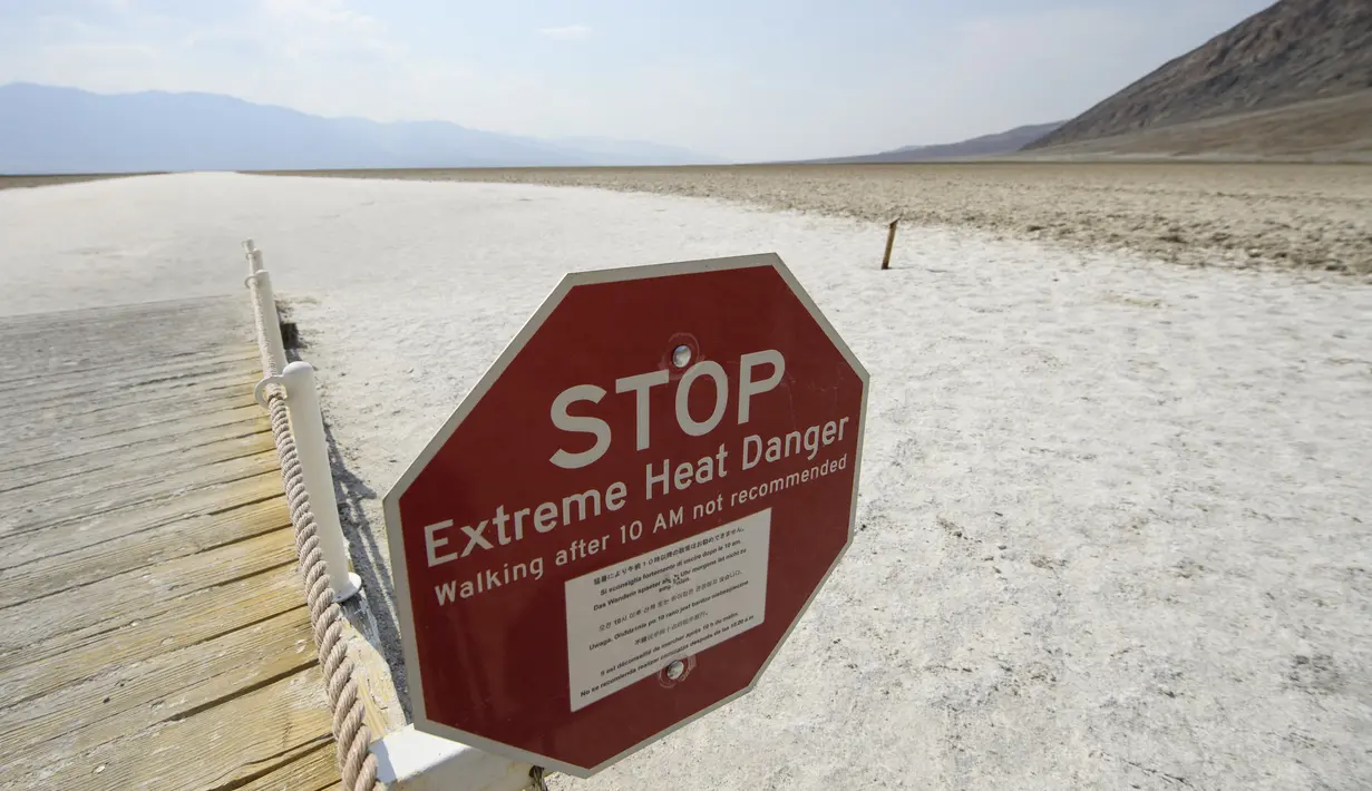 Tanda peringatan bahaya panas ekstrem di Badwater Basin, Taman Nasional Death Valley, California, Kamis (17/6/2021). Sebagian besar Amerika Serikat bagian barat bersiap menghadapi rekor gelombang panas minggu ini. (Patrick T. FALLON/AFP)