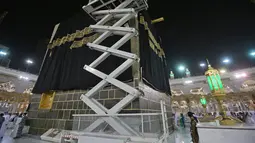 Petugas saat mengganti kain penutup Ka'bah (Kiswah) dengan yang baru di Masjidil Haram, kota suci Makkah, Arab Saudi (18/7/2021). Pergantian Kiswah rutin dilakukan pada musim haji, tepatnya pada 9 Zulhijah. (AFP Photo)