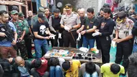 Petugas menunjukkan barang bukti dalam penggerebekan Kampung Boncos, Kota Bambu Selatan, Palmerah Jakarta Barat, Rabu (7/2). (Liputan6.com/ Ady Anugrahadi)