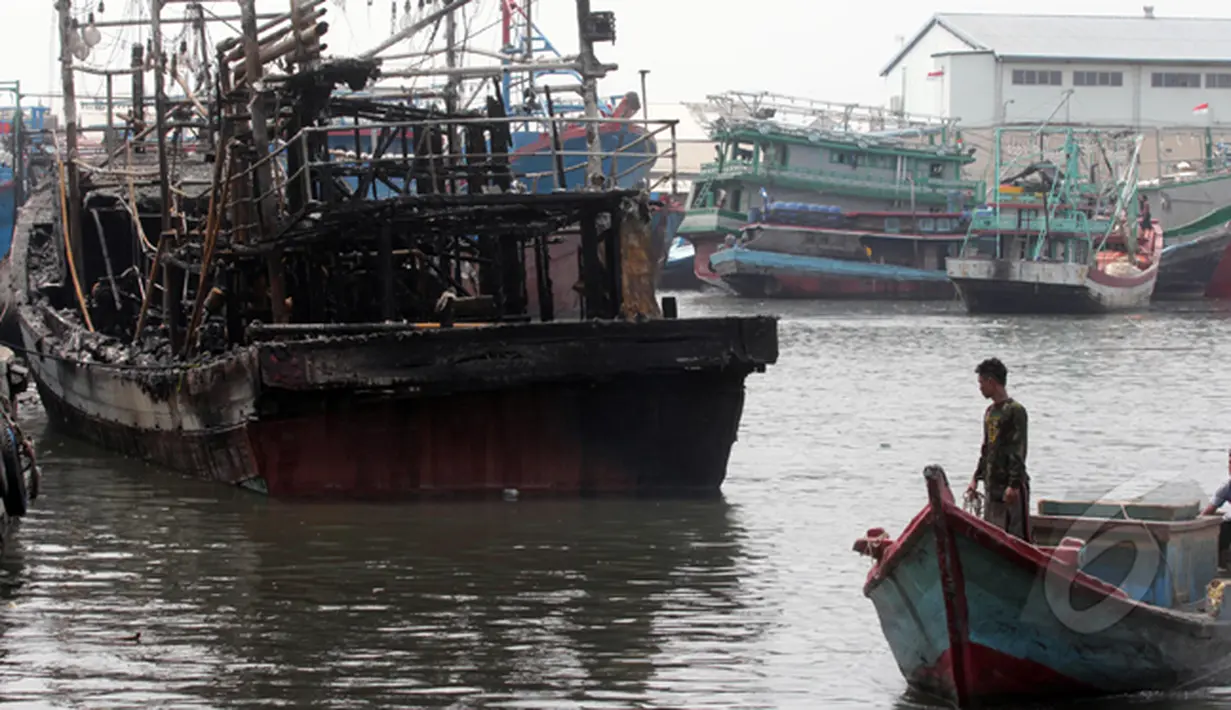Dua orang lelaki melihat kapal yang terbakar di Pelabuhan Muara Angke, Jakarta, Jumat (27/2/2015). Diduga kebakaran disebabkan korsleting listrik. Kerugian ditaksir mencapai ratusan juta. (Liputan6.com/Johan Tallo)