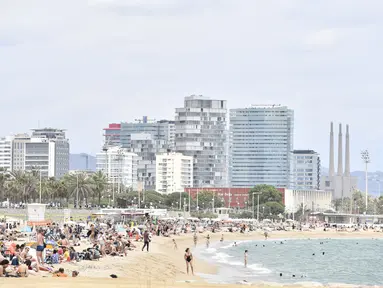 Orang-orang berjemur di Pantai Bogatell di Barcelona, Minggu (6/6/2021). Spanyol akan mengizinkan semua pelancong yang divaksinasi untuk mengunjungi negara itu mulai 7 Juni, dengan tujuan kembali menghidupkan industri perjalanan yang terpukul pandemi Covid-19. (Pau BARRENA/AFP)