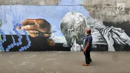 Seorang warga melihat mural bertema Islami di Gang Abdul Jabar, Jagakarsa, Jakarta, Senin (28/5). (Liputan6.com/Herman Zakharia)