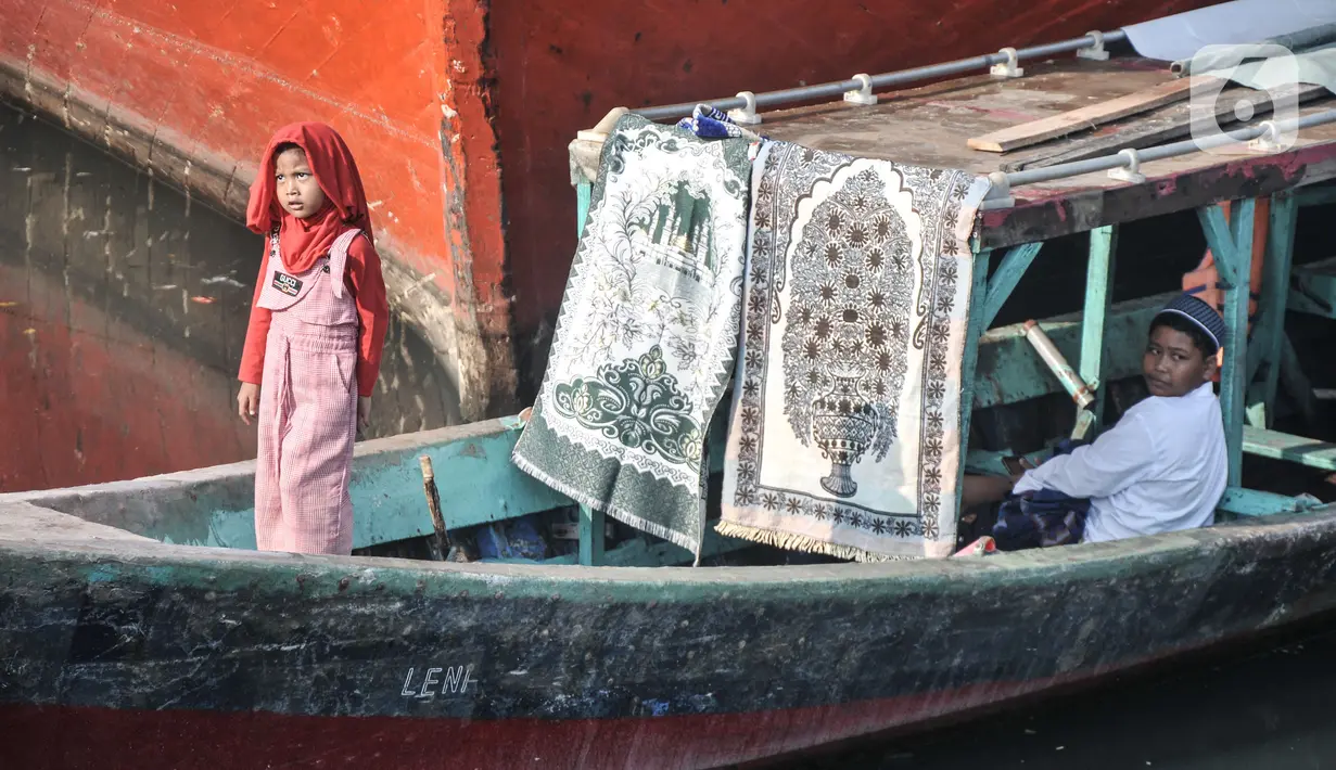 Anak-anak  menggunakan perahu sebagai transportasi menuju lokasi salat Idul Fitri 1444 H di Pelabuhan Sunda Kelapa, Jakarta, Sabtu (22/4/2023). (merdeka.com/Iqbal S. Nugroho)