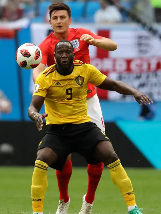 Penyerang Belgia, Romelu Lukaku berusaha mengontrol bola dari kawalan bek Inggris, Harry Maguire saat bertanding memperebutkan juara tiga Piala Dunia 2018 di Stadion St. Petersburg di St. Petersburg, Rusia, (14/7). (AP Photo/Petr David Josek)