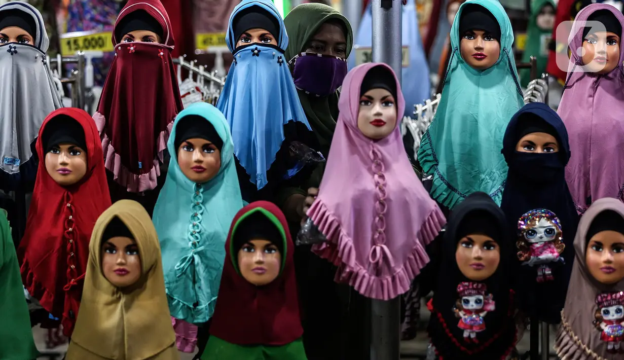 Pedagang gamis dan baju anak menata barang dagangannya di pasar Parung, Bogor, Jawa Barat, Kamis (18/2/2021). Akibat menurunnya omset penjualan gamis dan baju anak selama pandemi COVID-19, pedagang rela menurunkan harga agar menarik perhatian pembeli. (Liputan6.com/Johan Tallo)