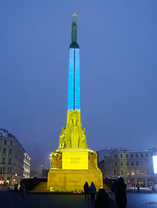 Monumen Kebebasan diterangi dengan warna bendera nasional Ukraina untuk menandai peringatan satu tahun invasi Rusia ke negara itu di Riga, Latvia, 24 Februari 2023. (AP Photo/Roman Koksarov)