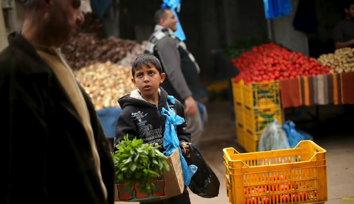 Mohammad al-Bana (10), Bocah Palestina menjual sayur di sebuah pasar di Kota Gaza (29/3). Bana yang masih bersekolah menghasilkan sekitar sekitar 10 Shekels ($ 2.5) per hari karena ayahnya sudah lagi tidak bekerja. (REUTERS/Mohammed Salem)