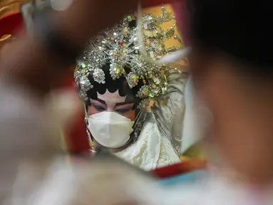 Seorang pemain opera Tiongkok yang mengenakan masker bersiap untuk tampil pada sebuah panggung di Bangkok, Rabu (6/10/2021). Sempat vakum, pertunjukan opera Tiongkok di Thailand kembali dihidupkan meski belakangan ini kasus harian Covid-19 kembali meningkat. (AP Photo/Sakchai Lalit)