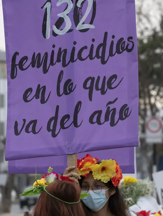 Rombongan teater Vichama melakukan prosesi kamar mayat berjudul "Kami Ingin Diri Sendiri Hidup!" sambil membawa tubuh tiruan dan menampilkan tanda-tanda kiasan pada malam Hari Anti Kekerasan Terhadap Perempuan di Villa El Salvador, Lima, Peru, 24 November 2021. (Cris BOURONCLE/AFP)