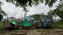 Para pekerja berjalan melewati kapal-kapal yang sedang diperbaiki di galangan kapal di tepi Sungai Yangon, yang terletak di pinggiran Yangon, Myanmar (30/7/2019). (AFP Phot/Sai Aung Main)