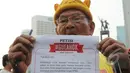 Seorang lelaki tua memperlihatkan petisi #GueAhok di Bundaran HI, Jakarta, Minggu (1/3/2015). Aksi mereka sebagai bentuk dukungan kepada Ahok yang ingin membongkar dana siluman di Pemprov DKI (Liputan6.com/Herman Zakharia)