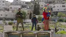 Pemukim Yahudi yang mengenakan kostum merayakan Hari Raya Purim saat tentara mengamankan pawai di Kota Hebron, Tepi Barat, 7 Maret 2023. Para pemukim setiap tahun mengadakan parade perayaan Hari Raya Purim untuk memperingati keselamatan orang Yahudi dari genosida di Persia kuno, seperti yang diceritakan dalam Gulungan Ester. (AP Photo/Ohad Zwigenberg)