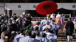 Para pelempar kacang berjalan sebelum "Mame-maki," upacara pelemparan kacang, di kuil Buddha Zojoji di Tokyo, 3 Februari 2022. Ritual yang diyakini membawa keberuntungan dan mengusir kejahatan dilakukan setiap tahun untuk menandai awal musim semi dalam kalender lunar. (AP Photo/Eugene Hoshiko)