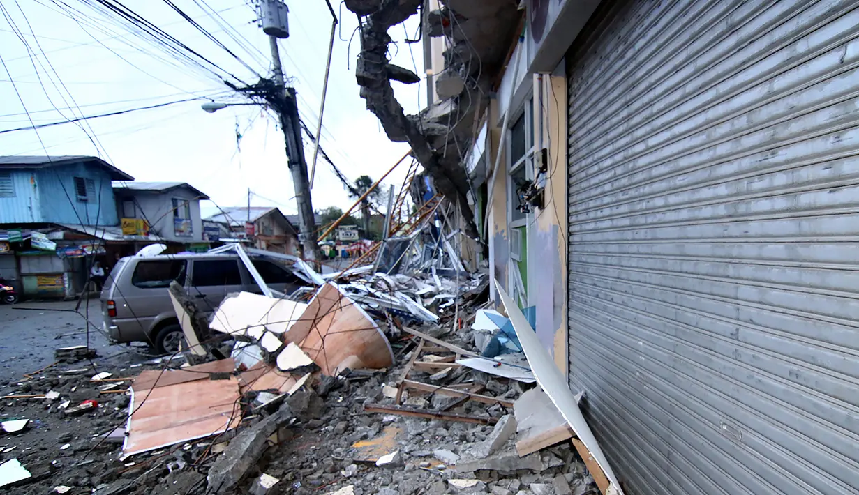 Sebuah mobil yang terparkir terjebak di bawah puing-puing bangunan yang runtuh akibat gempa 6,5 SR yang melanda Surigao City, Pulau Mindanao, Filipina (11/2). (AFP/Erwin Mascarinas)