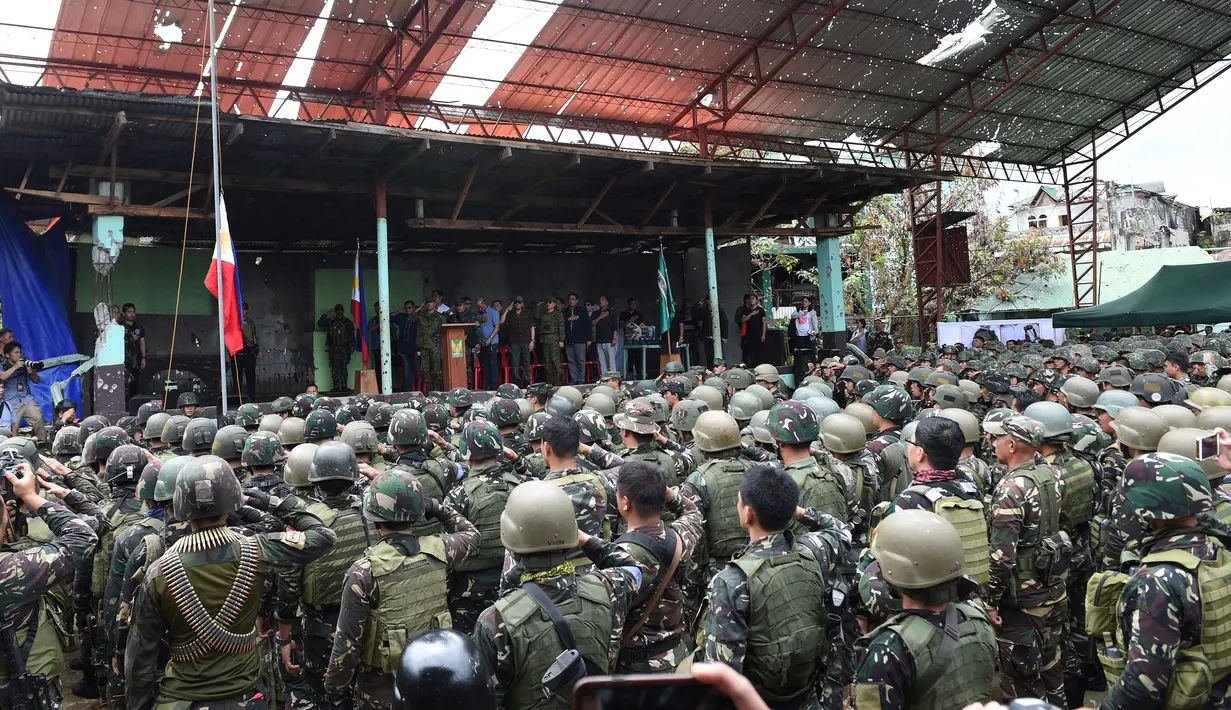 Presiden Filipina, Rodrigo Duterte bersama para tentara memberi hormat kepada bendera Filipina usai mengumumkan pembebasan kota Marawi di Filipina (17/10). (AFP Photo/Ted Aljibe)