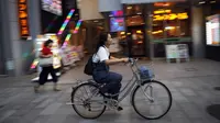 Seorang wanita mengendarai sepedanya di sebuah jalan di Nagoya, Jepang (24/9/2019). Kota Nagoya terletak di Daratan rendah Nōbi, bagian barat daya Prefektur Aichi. (AP Photo/Christophe Ena)