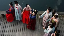 Sejumlah wanita mengenakan kostum Dinasti Tang saat mengunjungi Danau Barat di Hangzhou di provinsi Zhejiang timur China (31/3). Bahan pakaian Dinasti Tang terbuat dari sutra dan terkenal karena kelembutan dan ringan.  (AFP Photo/China Out)