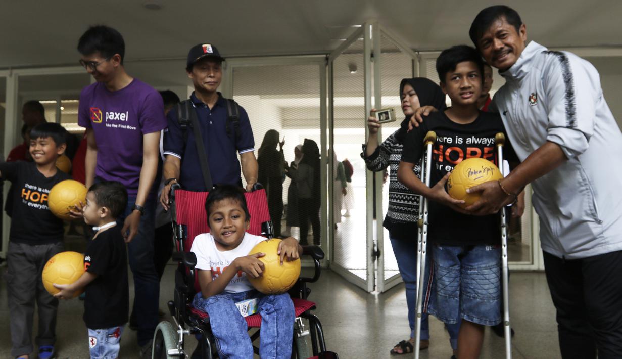 Pelatih Timnas Indonesia U-23, Indra Sjafri, memberikan bola kepada anak-anak yang datang ke Stadion Madya, Jakarta, Rabu (13/3). Sejumlah anak dari Yayasan Rumah Harapan Indonesia datang menemui Timnas U-23 (Bola.com/Vitalis Yogi Trisna)