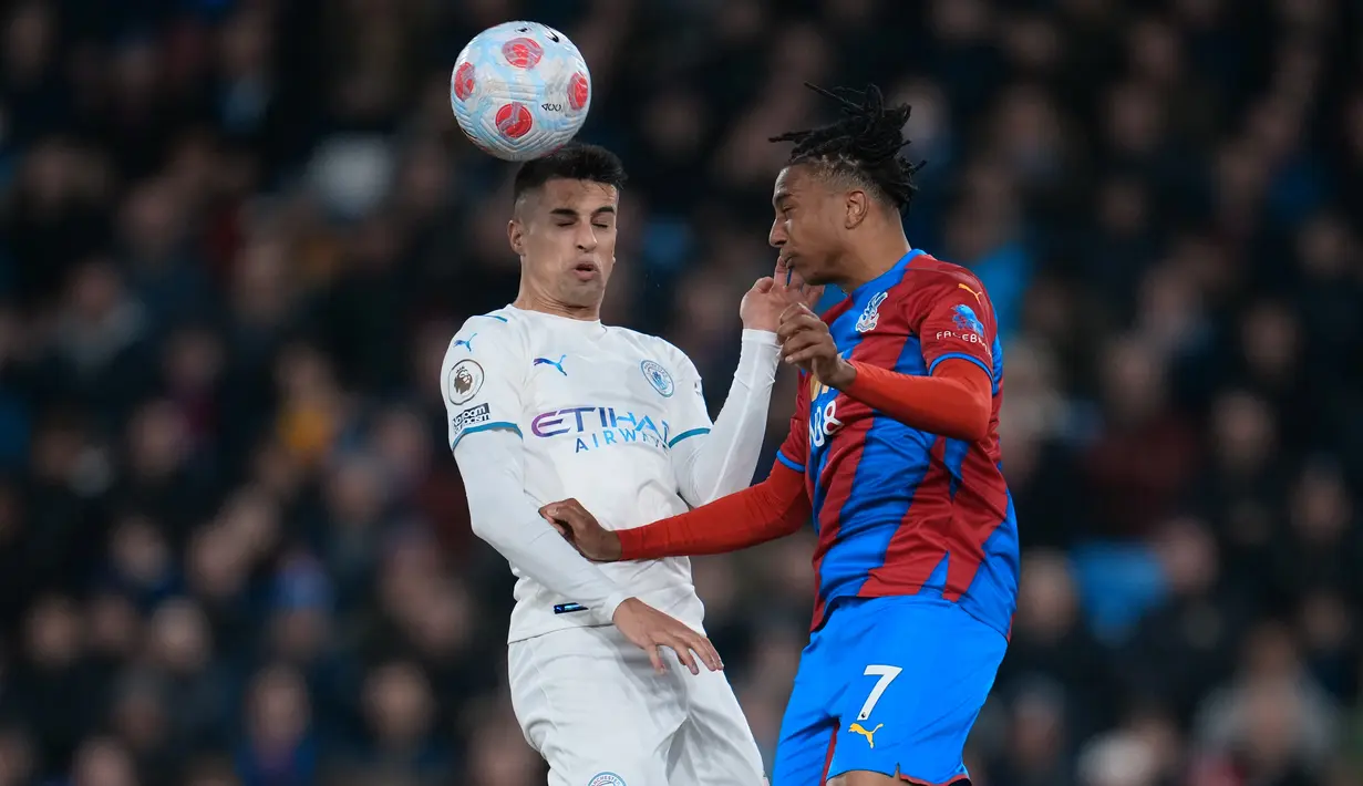 Bek Manchester City, Joao Cancelo berebut bola udara dengan  pemain Crystal Palace, Michael Olise dalam pertandingan lanjutan Liga Inggris di Selhurst Park, London, Selasa (15/3/2022). Manchester City bermain imbang atas Crystal Palace 0-0. (AP Photo/Matt Dunham)
