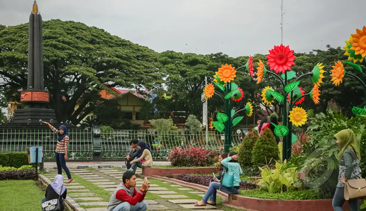 Sejumlah muda-mudi asyik berfoto di Alun-alun Tugu Kota Malang, Rabu (21/1/2015). (Liputan6.com/Faizal Fanani)