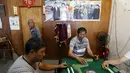 Para nelayan saat bermain mahjong di depan poster Presiden China Xi Jinping saat perahunya bersandar akibat badai Topan Chan-Hom yang mendekati wilayah Wenling, Zhejiang, China (8/7/2015). (REUTERS/William Hong)