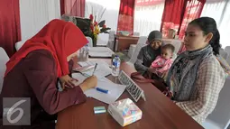 Seorang ibu mendaftar sebelum melakukan vaksinasi ulang anaknya di RS Polri Kramatjati, Jakarta Timur, Kamis (21/7). RS Polri Kramatjati buka posko pelayan vaksinasi ulang untuk warga. (Liputan6.com/Yoppy Renato)