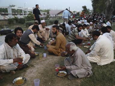 Orang-orang berbuka puasa selama bulan suci Ramadhan di pinggir jalan, di Islamabad, Pakistan, Selasa, 5 April 2022. Umat Muslim di seluruh dunia menjalankan Ramadhan, di mana mereka menahan diri dari makan, minum, merokok dan seks dari fajar hingga senja. (AP Photo/Rahmat Gul)