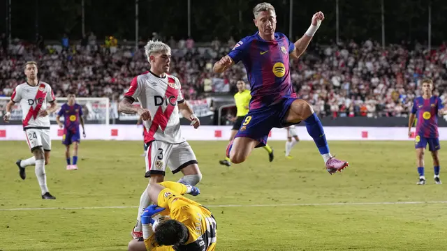 Striker Barcelona Robert Lewandowski melompat melewati adangan kiper Rayo Vallecano di pekan ketiga La Liga 2025/2026 di Estadio de Vallecas, Senin (01/09/2025). (AP Photo/Manu Fernandez).