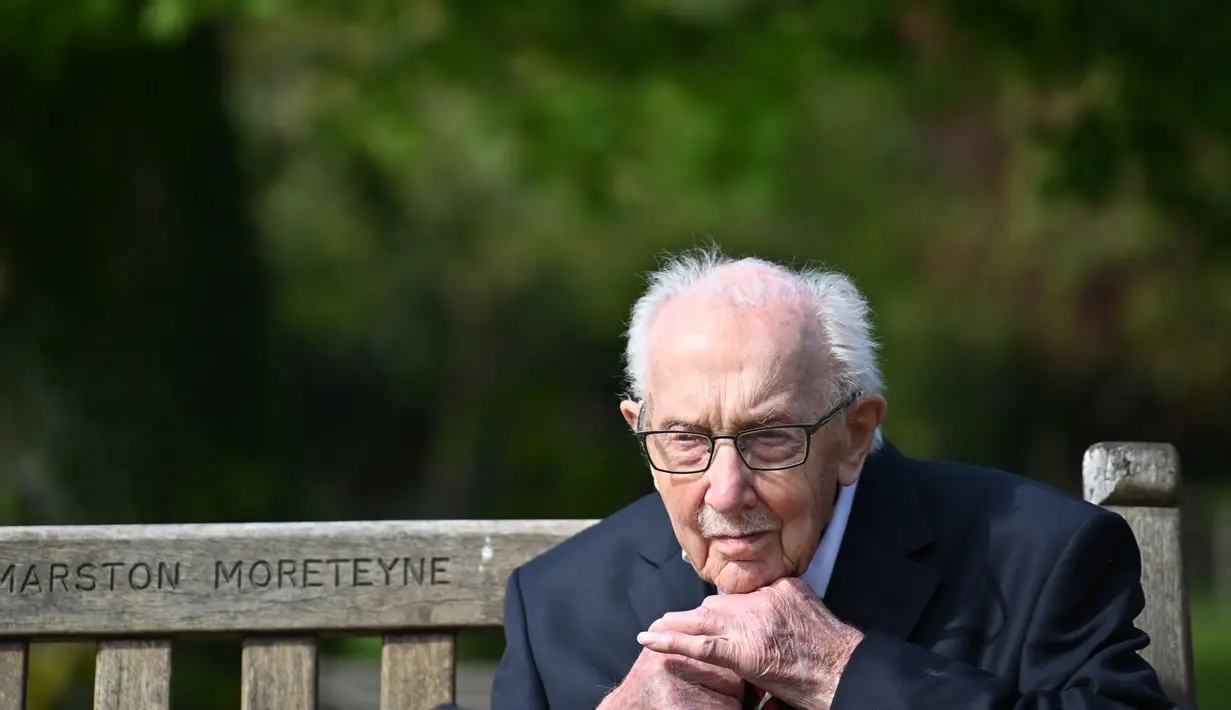Veteran Perang Dunia II Kapten Tom Moore (99) berpose di bangku kebunnya di Marston Moretaine, London, 16 April 2020. Moore mengumpulkan donasi lebih dari 16 juta dolar untuk National Health Service (NHS) dengan berjalan 100 kali bolak-balik jarak 25 meter di taman rumahnya. (Justin TALLIS/AFP)